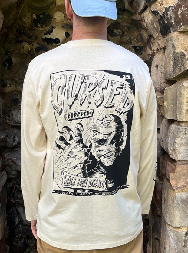 Person wearing a long-sleeve shirt with a graphic design in front of a stone wall.